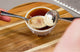 Skimming grounds from a coffee cupping bowl with two spoons during a tasting session