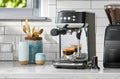 Breville Bambino Plus pulling two espresso shots beside a Baratza grinder on a tiled counter