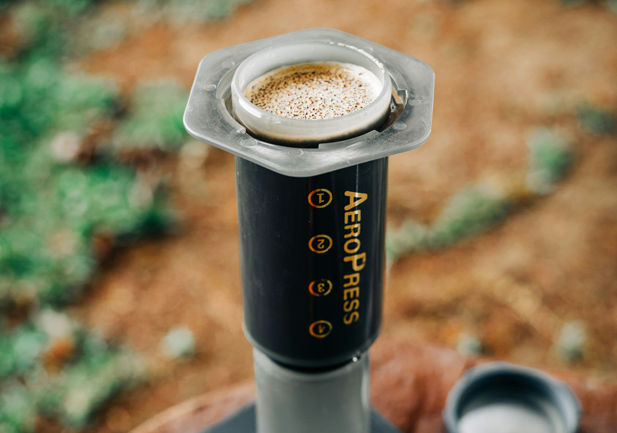 AeroPress coffee maker brewing outdoors with coffee grounds in the filter cap, perfect for portable coffee on the go