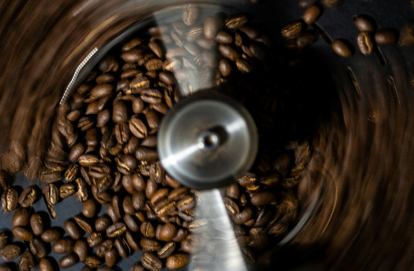An overhead view of coffee beans spinning inside a blade grinder