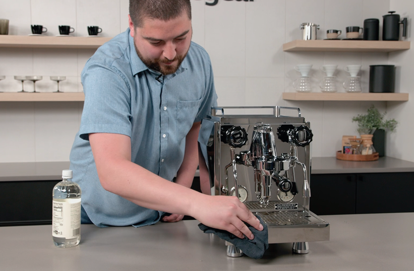 Barista wiping down a stainless steel home espresso machine with a microfiber cloth - Seattle Coffee Gear