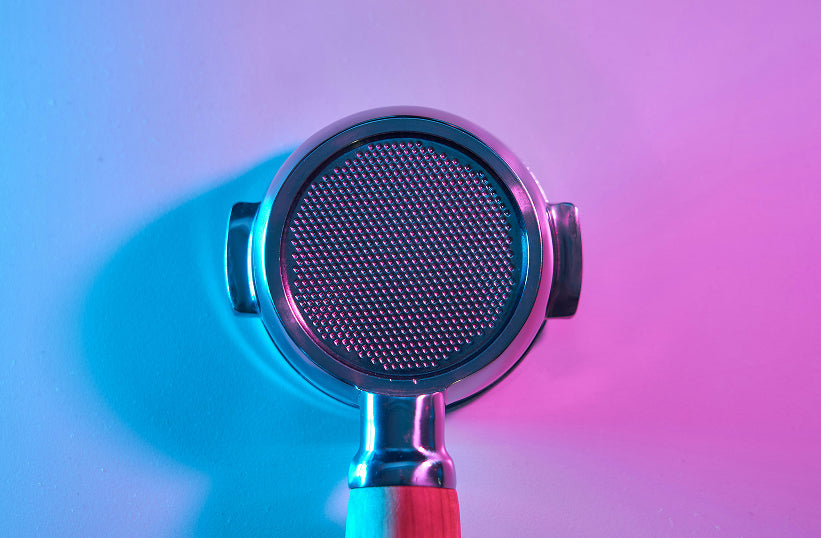 A bottomless portafilter basket shown from above under colorful purple and blue lighting