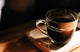 Glass cup of dark decaf espresso with crema on a wooden tray