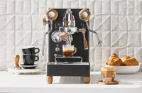 LELIT Mara X3 espresso machine in black with wood accents pulling a shot on a counter