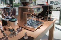 Espresso machines and grinders on display at a Seattle Coffee Gear showroom counter