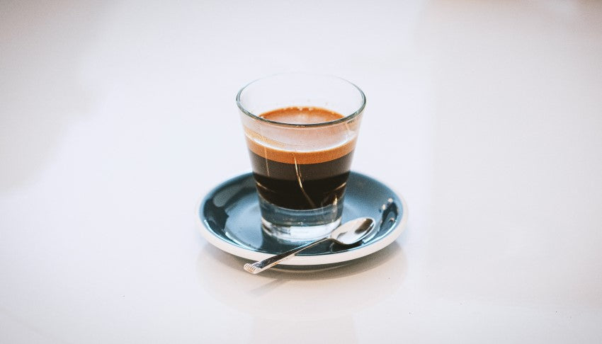 Espresso in a shot glass on a small plate - By Adi Goldstein for Unsplash - Seattle Coffee Gear