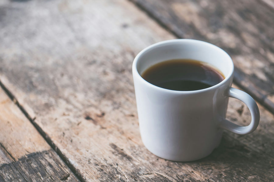 Coffee in a coffee cup on a wood plank - by Jessica Lewis